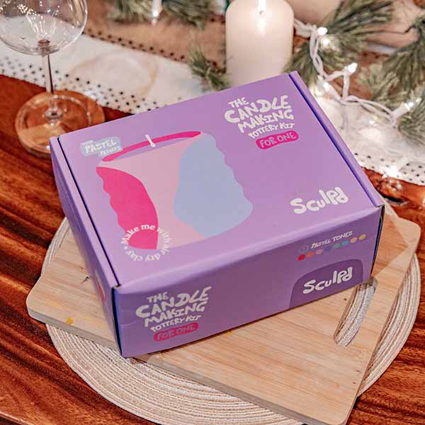 Sculpd Candle Making Kit for One box in a cozy setup, surrounded by candles and festive greenery