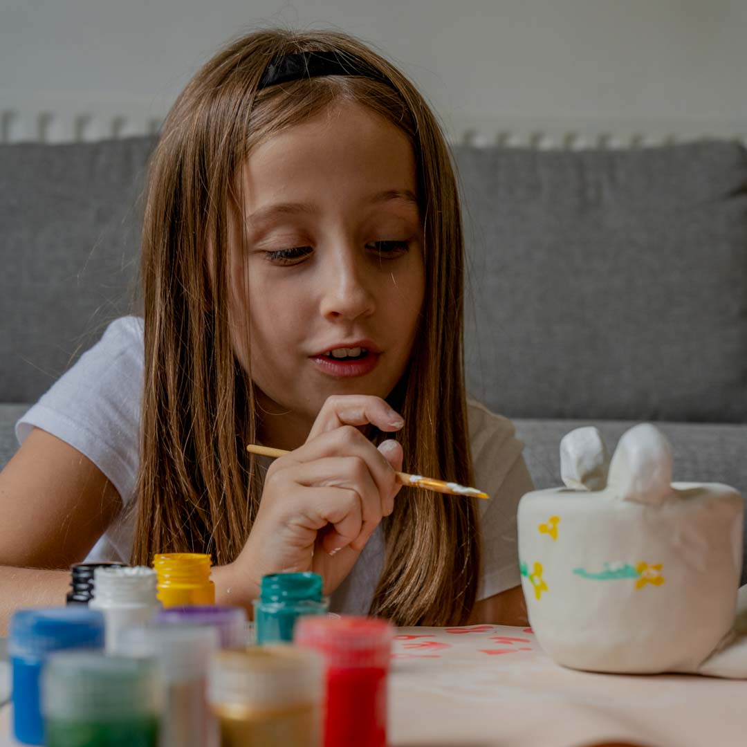 Girl painting her animal pottery pinch pot