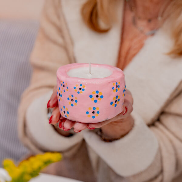 A woman holding aloft a pink candle made using Sculpd Candle Making Kit