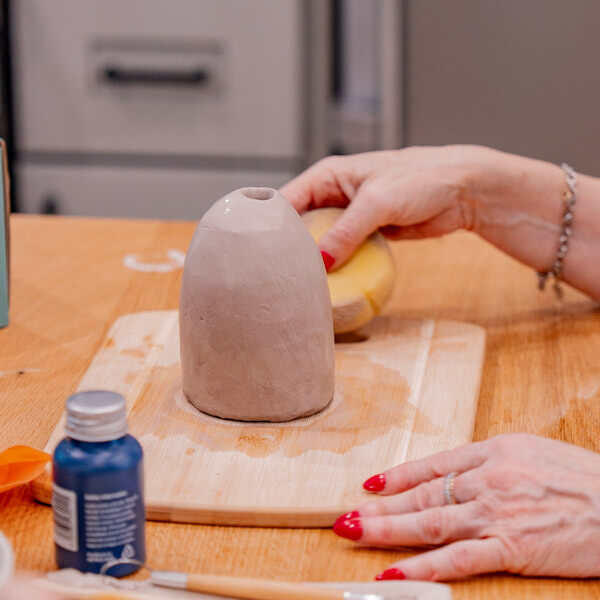 Woman's hands sculpt a clay piece with a sponge and tools from Sculpd Pottery Kit