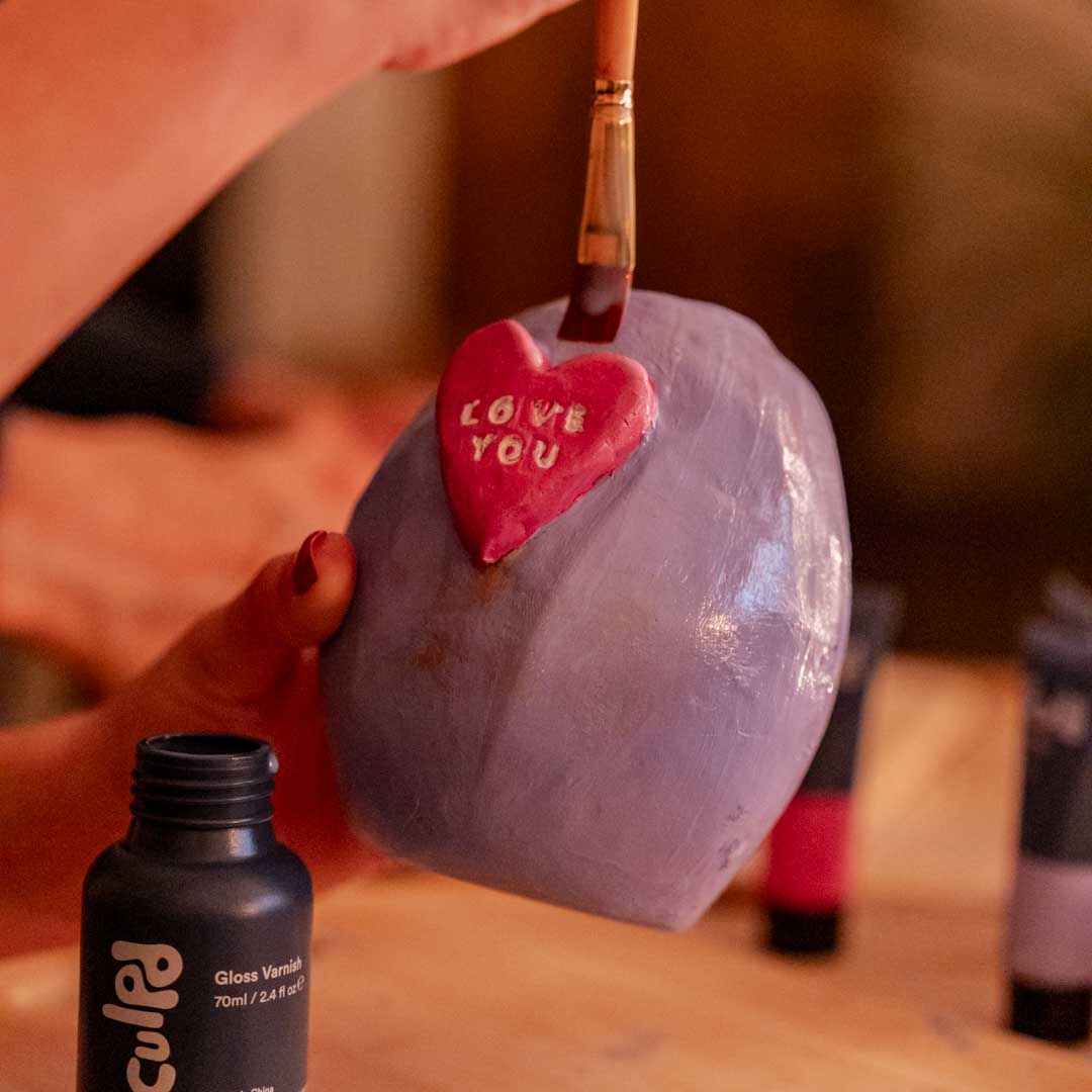 Sculpd Pottery vase with a heart and stamped letters saying 'Love You' being varnished by Sculpd Gloss varnish