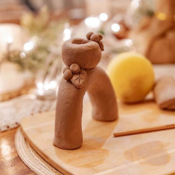 A cozy clay crafting session with a small figure, surrounded by pottery tools using Sculpd Pottery Kit