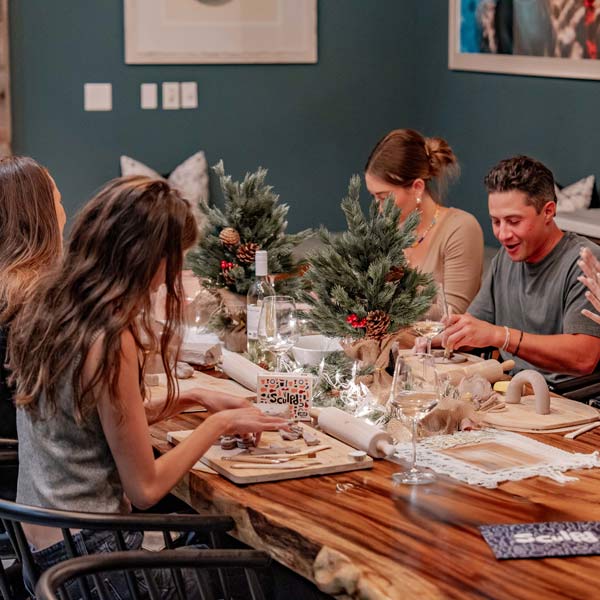 A festive gathering with friends enjoying a Sculpd Pottery Kit night, surrounded by holiday decorations and cozy vibes