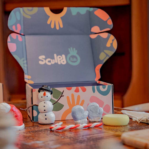 Opened Sculpd Kids Pottery Box with Christmas themed clay pieces in front of it on a table