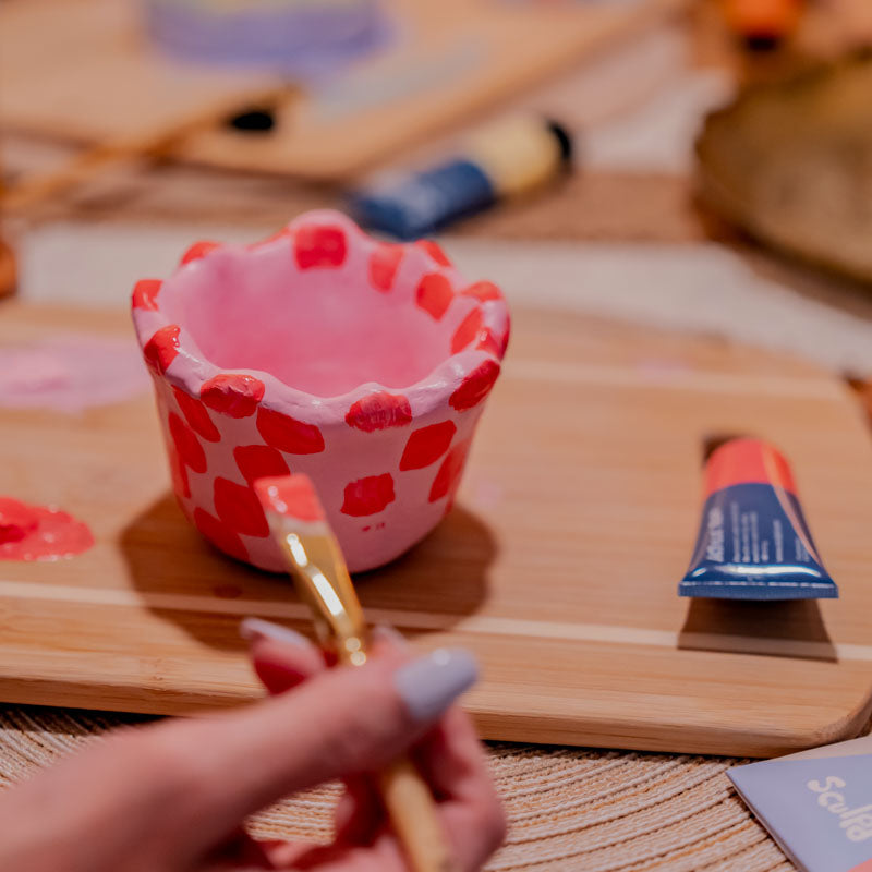 Sculpd Candle Making Kit Pot being painted in red and pink with a wooden brush