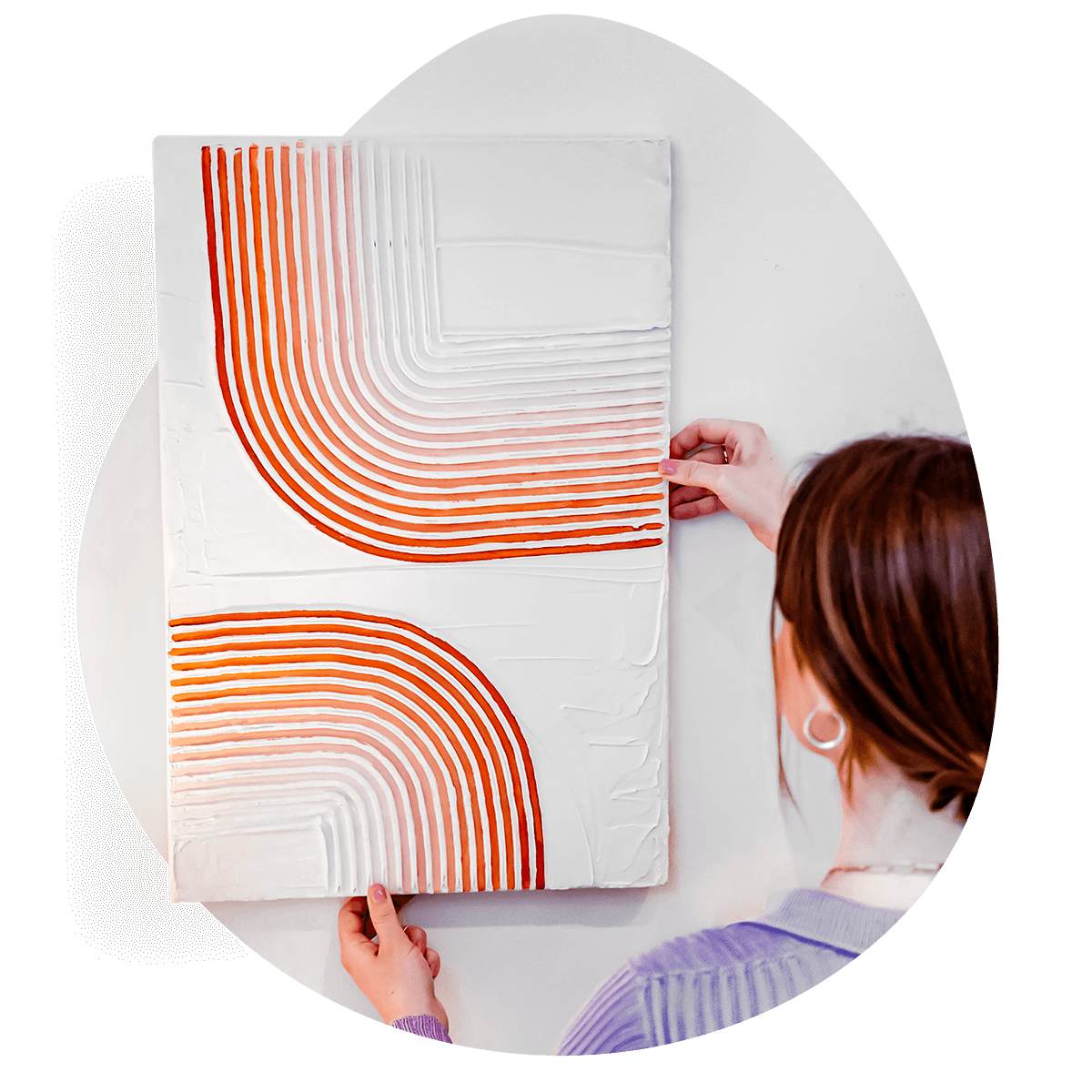 A person holding aloft a textured canvas artwork featuring intricate, raised patterns in white and orange made out of Sculpd Textured Canvas Kit